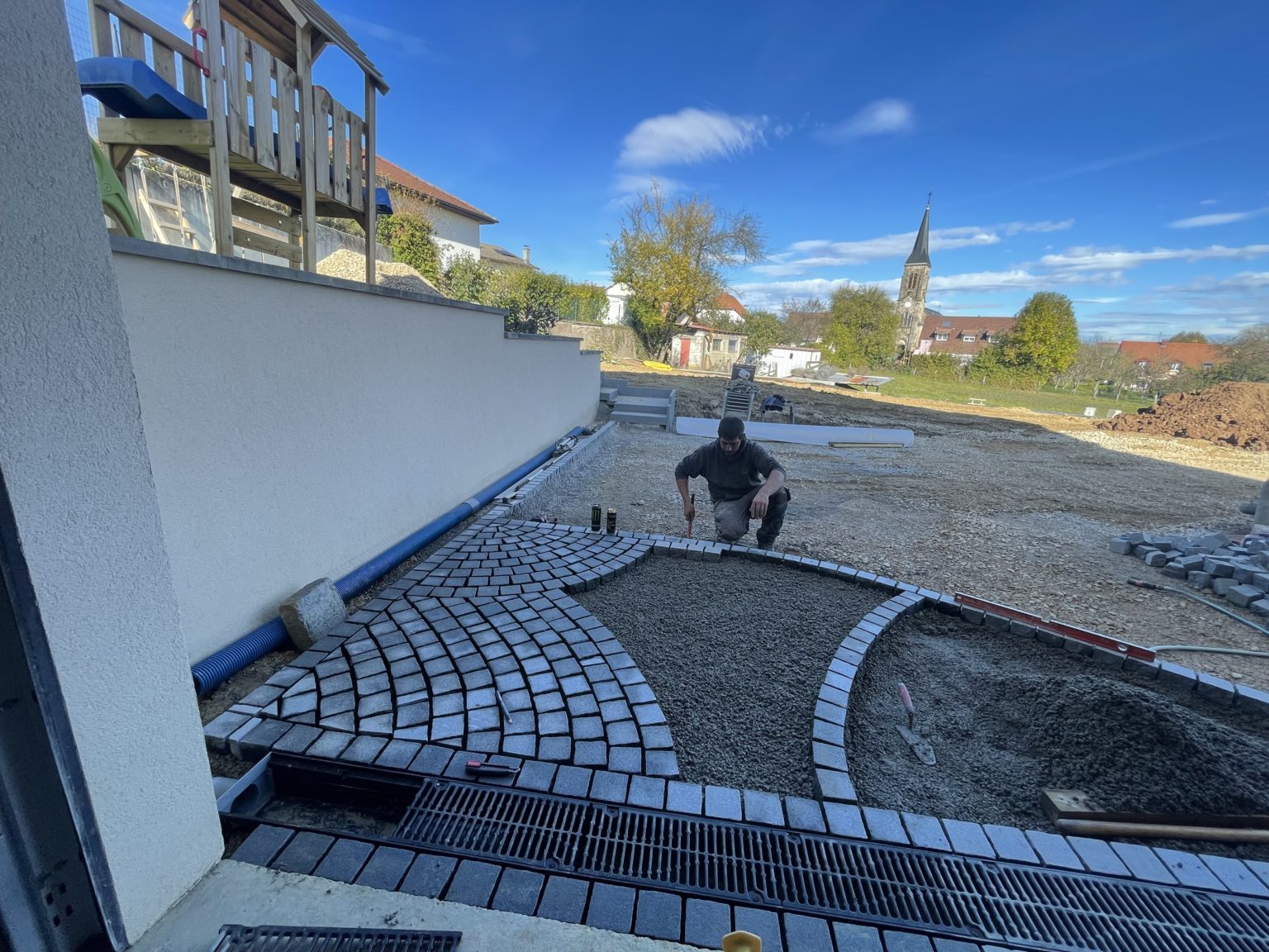 Ouvrier de Julien Nature Services posant les pavés d'une cour sur un chantier