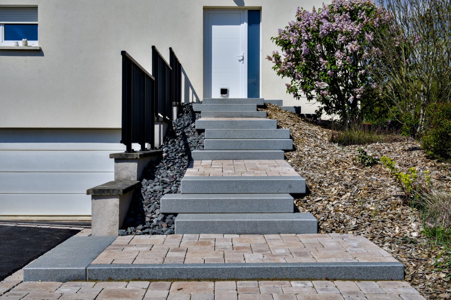 Escalier en dalles et allée en pavés devant une entrée de maison